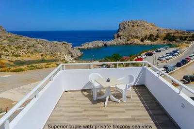 a balcony with a table and chairs overlooking the ocean at St. Paul's Bay View Suites in Líndos