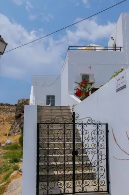 a white house with a gate and stairs at St. Paul's Bay View Suites in Líndos