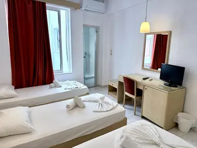 a room with three beds and a desk and a television at Savoy City Hotel in Rhodes Town