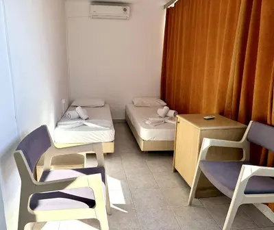 a small room with two beds and a table and chairs at Savoy City Hotel in Rhodes Town