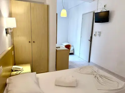 a room with a bed with a phone and a room with a door at Savoy City Hotel in Rhodes Town