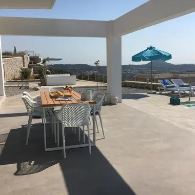 a table and chairs on a patio with an umbrella at Luxury Villa Hera with Private Pool in Afantou
