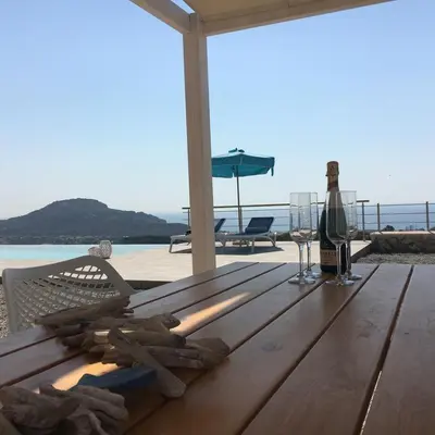 a wooden table with a bottle of wine on a beach at Luxury Villa Hera with Private Pool in Afantou