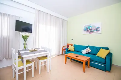 a living room with a blue couch and a table at Kahlua Hotel Apartments in Rhodes Town