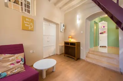a living room with a couch and a table and stairs at Colourful Home, Medieval Town Rhodes in Rhodes Town