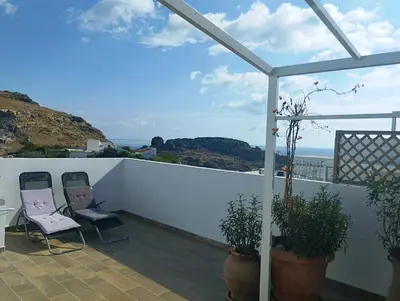 a balcony with two chairs and a view of the ocean at Nikelen Lindian Exclusive Apartments in Líndos