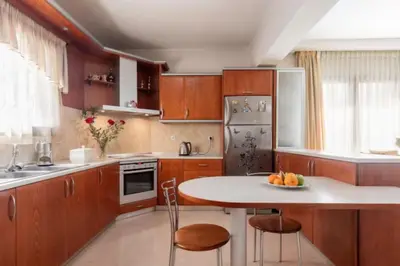 a kitchen with wooden cabinets and a table and chairs at Savvinas House Faliraki-Traganou Beach in Faliraki