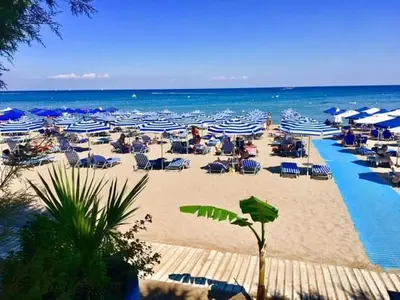 a beach with chairs and umbrellas and the ocean at Savvinas House Faliraki-Traganou Beach in Faliraki