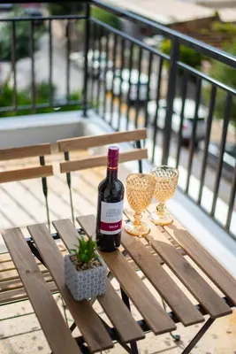 a bottle of wine and two wine glasses on a wooden bench at TownHall Apartment's in Rhodes Town