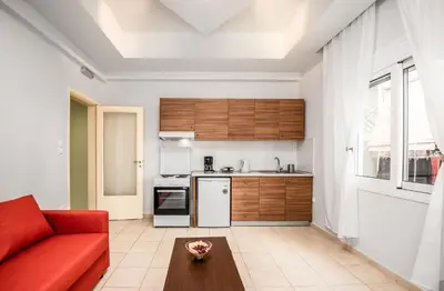 a living room with a red couch and a kitchen at TownHall Apartment's in Rhodes Town
