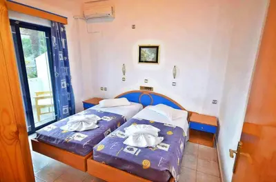 two beds in a room with towels on them at Nitsa's Apartments in Megálon Choríon