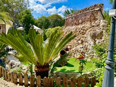 a garden with a palm tree in front of a building at Nicole Luxury Villas in Koskinou