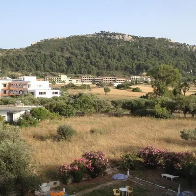 a view of a mountain with buildings and flowers at Ikaros Studios in Faliraki
