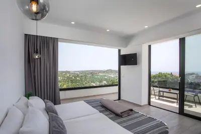 a bedroom with a white bed and large windows at Habitat Inn Faliraki View Villa Rhodes in Kalithies