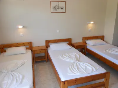 a room with three beds with white sheets at Villa Olive Grove in Afantou