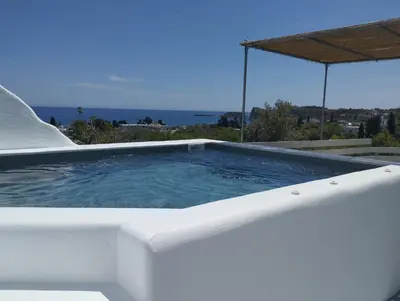 a large white pool with a view of the ocean at Filia Bungalow in Archangelos