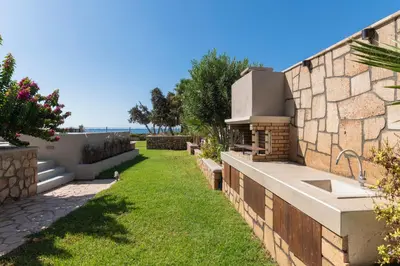a backyard with a stone wall and grass at Villa Del Nonno in Lardos