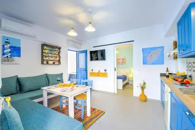 a kitchen and living room with blue cabinets and a table at Koskinou Traditional Houses in Koskinou