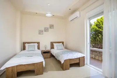 two beds in a room with a window at Villa Linda Tsambika Afandou in Afantou