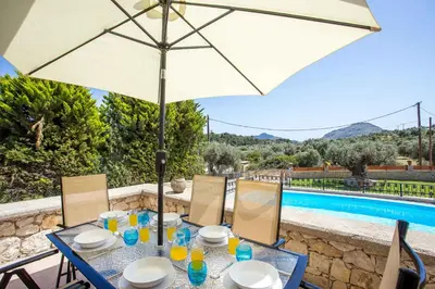 a table with an umbrella next to a swimming pool at Villa Linda Tsambika Afandou in Afantou