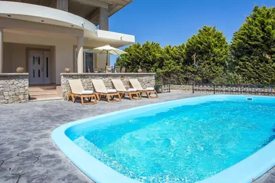 a swimming pool with chairs and a house at Villa Linda Tsambika Afandou in Afantou