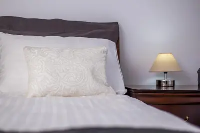 a bed with a white pillow and a table with a lamp at Villa Linda Tsambika Afandou in Afantou