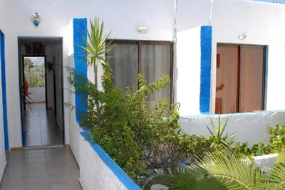 a house with blue and white walls and plants at Anthula Sun in Archangelos