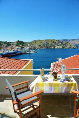 a table and chairs on a balcony with a view of the water at Pitini Nikos house in Symi