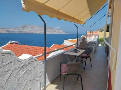 a balcony with chairs and a view of the water at Pitini Nikos house in Symi
