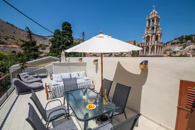 a patio with a table and chairs and an umbrella at Villa Elion in Symi