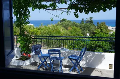 two blue chairs and a statue of a dog on a balcony at Stegna Breeze in Archangelos