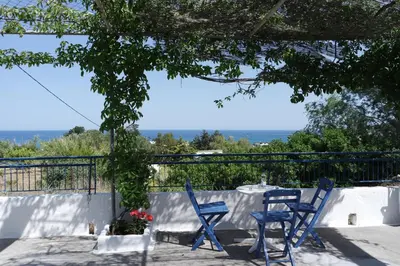 two blue chairs and a table on a patio at Stegna Breeze in Archangelos