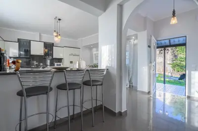 a kitchen with a bar with stools at Fontana Luxury Villa Salakos With Pool Near Beach in Sálakos
