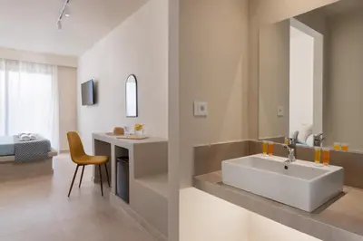 a bathroom with a sink and a bedroom at Olive Garden Hotel in Lardos