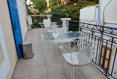 a balcony with a glass table and chairs on it at Anastasia Hotel in Symi