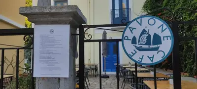 a sign on a gate with tables and chairs at Anastasia Hotel in Symi