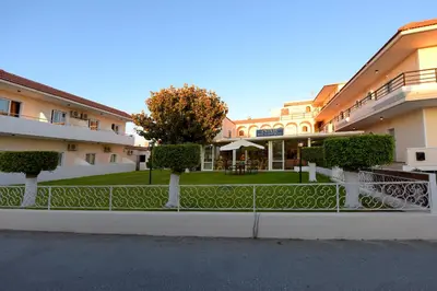 a building with a fence in front of a yard at Anixis Hotel & Apartments in Ialyssos
