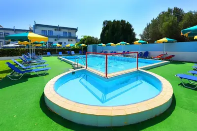 a large swimming pool with chairs and umbrellas at Anixis Hotel & Apartments in Ialyssos