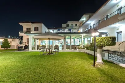 a patio with a table and an umbrella in front of a building at Anixis Hotel & Apartments in Ialyssos