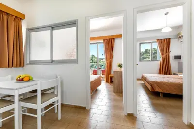 a room with a table and a bedroom with a bed at Anixis Hotel & Apartments in Ialyssos