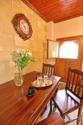 a dining room table with a vase of flowers and a clock at Athina house in Rhodes Town