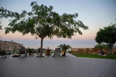 a patio with a tree and a table and chairs at Blue View Stegna House in Archangelos