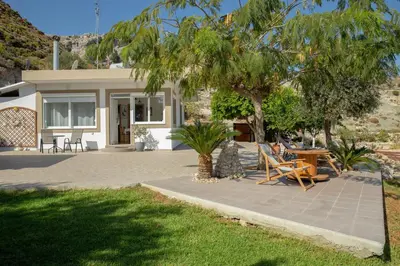 a patio with chairs and a table in front of a house at Blue View Stegna House in Archangelos