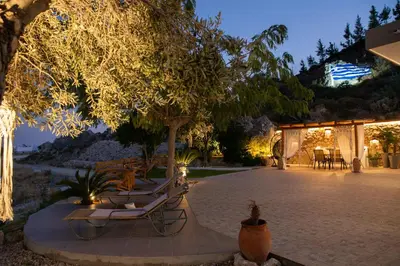 a patio with chairs and trees at night at Blue View Stegna House in Archangelos
