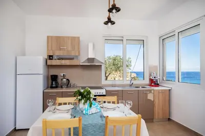 a kitchen with a table with chairs and a refrigerator at Blue View Stegna House in Archangelos