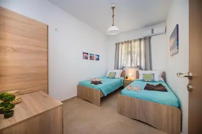 a room with two beds and a table in it at Blue View Stegna House in Archangelos