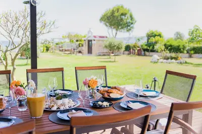 a wooden table with plates and bowls of food on it at Nastazia Luxury Beach House in Ialyssos