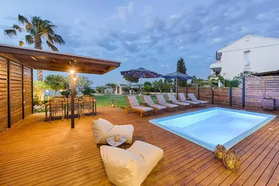 a deck with a pool and chairs and a table at Nastazia Luxury Beach House in Ialyssos