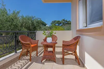 a balcony with three chairs and a table with a vase on it at Lina's Amazing House in Ialysos in Ixia