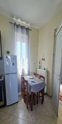 a kitchen with a table and a white refrigerator at Retas apartment up in Kremasti